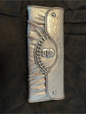 Juicy Couture Silver Leather Woman’s Clutch/Wallet with silver chain trim.